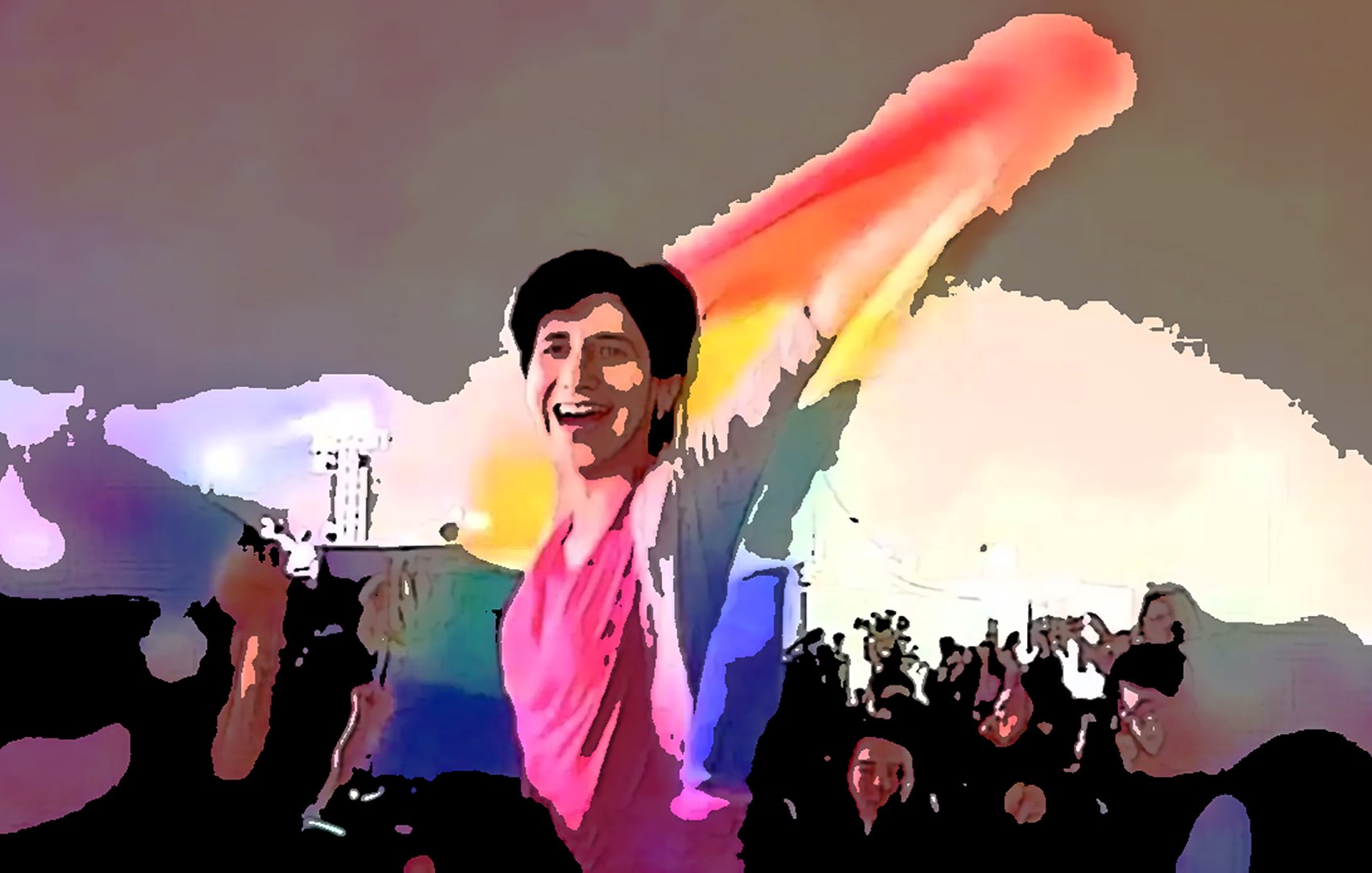 En la imagen se puede ver a una persona sonriente que sostiene una bandera de colores del arcoíris, símbolo del movimiento LGBTQ+. Está en un ambiente festivo, probablemente en un evento o celebración, rodeada de una multitud que también parece estar disfrutando del momento. La escena transmite una sensación de alegría y celebración de la diversidad.