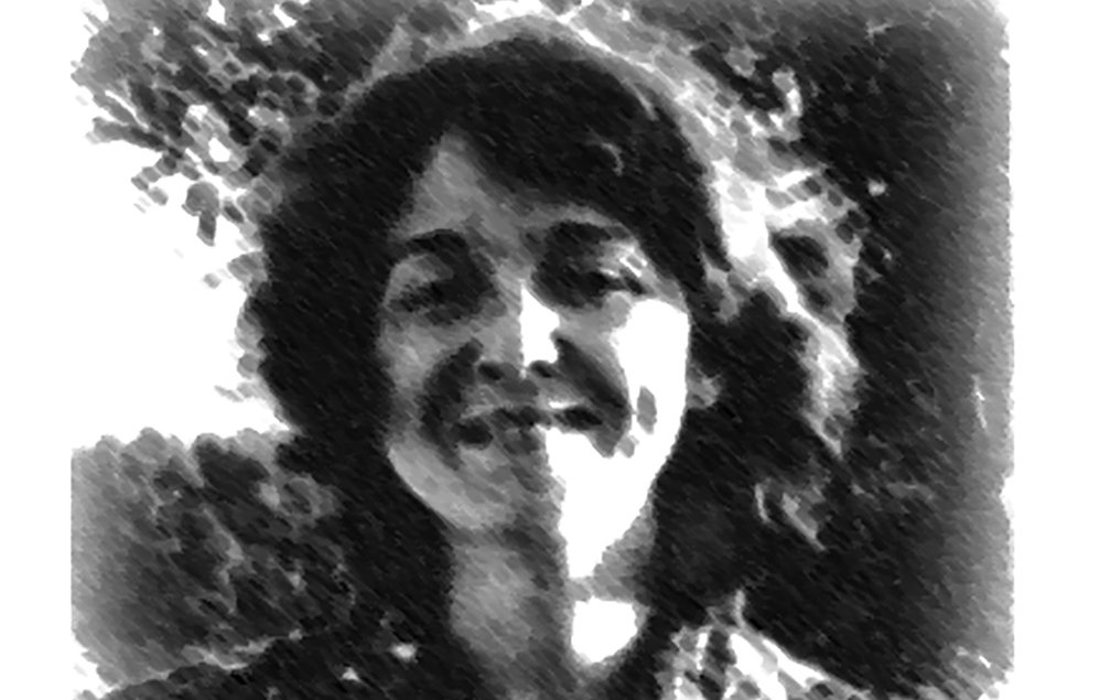 تصویر یک زن را نشان می‌دهد که با لبخند به دوربین نگاه می‌کند. او لباس گلداری با الگوهای مشخص پوشیده و موهای فر و لطیفی دارد. نور طبیعی از عقب او می‌تابد و باعث شده که تصویر حالتی نرم و هنری به خود بگیرد. پس‌زمینه نیز شامل درختانی است که جلوه‌ای زیبا به تصویر داده‌اند.