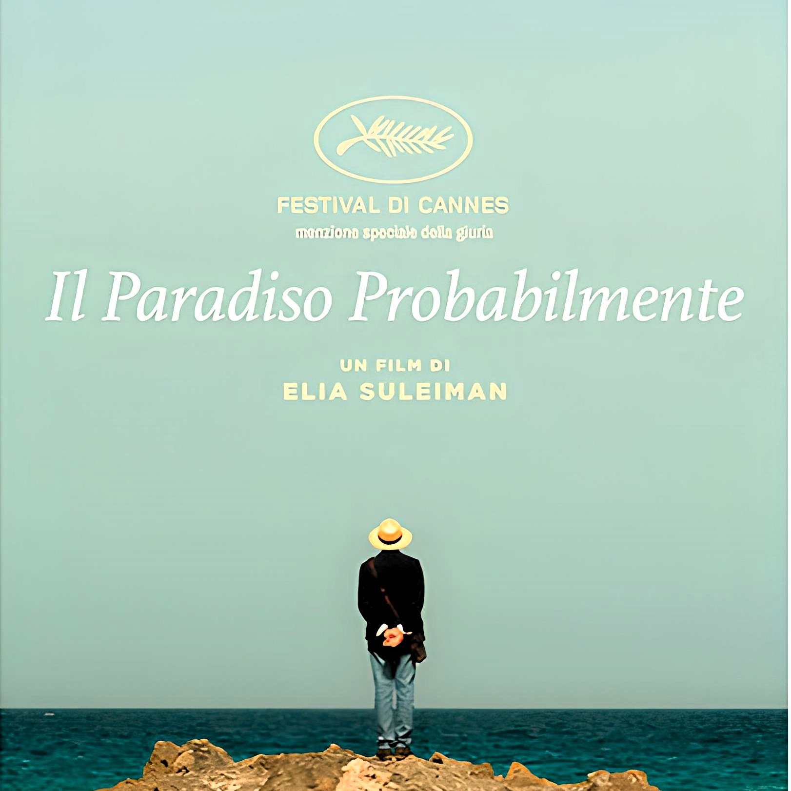 L'immagine sembra rappresentare un poster di un film intitolato "It Must Be Heaven", diretto da Elia Suleiman. In primo piano, c'è una figura umana di spalle, vestita con abiti leggeri e un cappello, che si trova su una scogliera e osserva l'orizzonte. Sullo sfondo, si vede un cielo sereno e un mare blu, creando un'atmosfera di tranquillità e contemplazione. Il titolo del film e il nome del regista sono scritti in caratteri chiari, dando risalto alla scena.