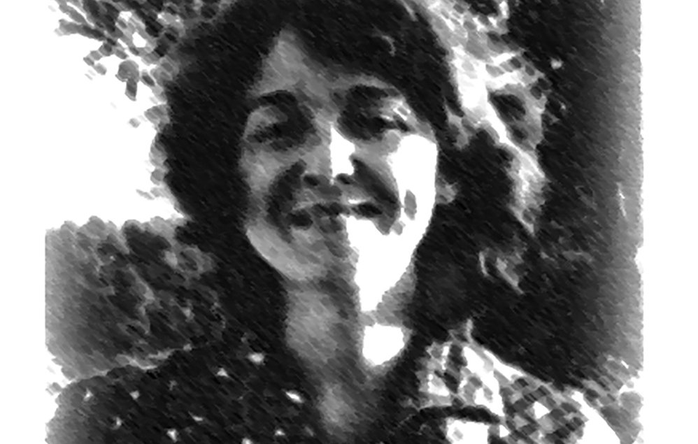 L'image montre une femme avec des cheveux bouclés et un sourire chaleureux. Elle porte une chemise à motifs. L'arrière-plan est flou, suggérant un environnement naturel. L'effet visuel donne une impression de dessin en noir et blanc, ajoutant une touche artistique à la scène.