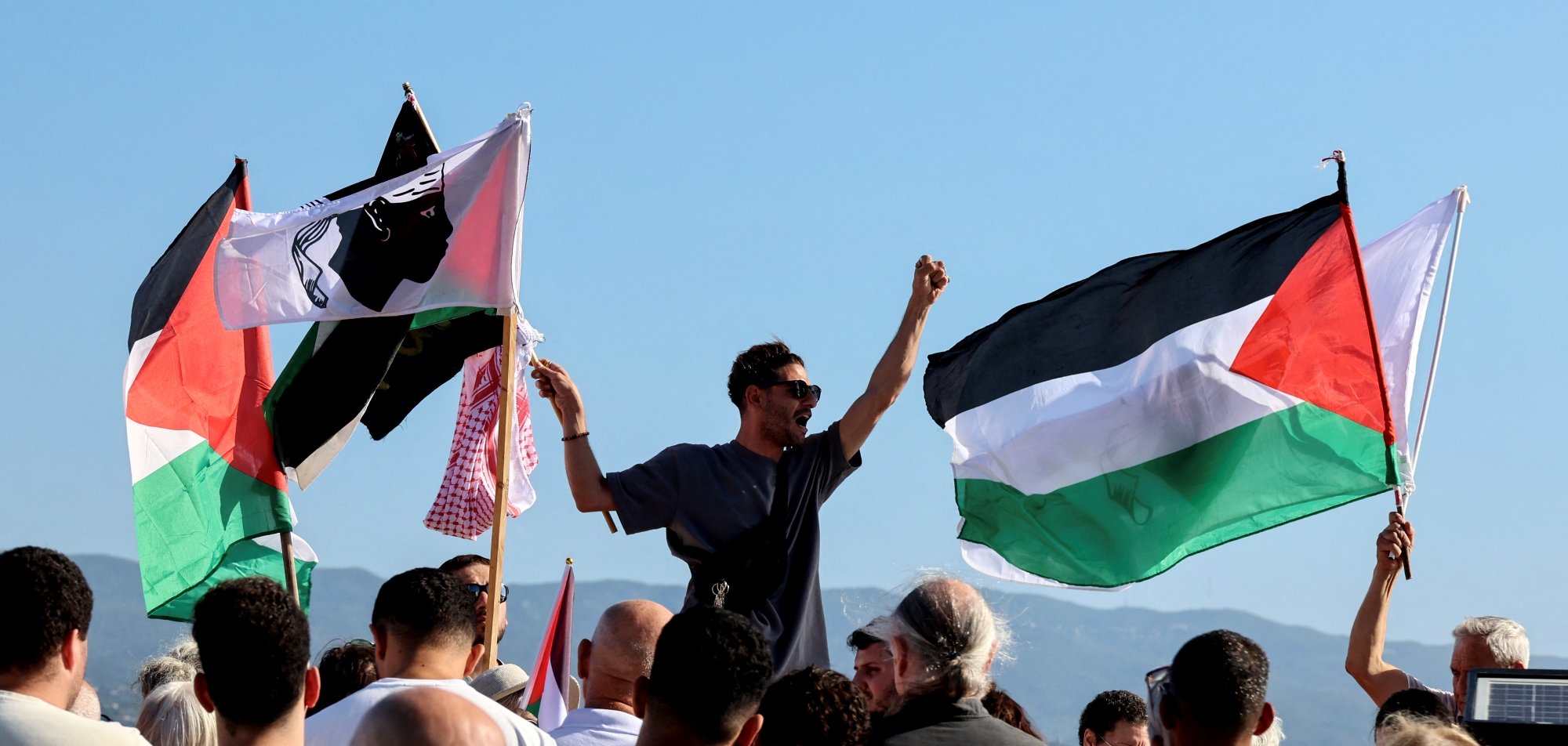 Manifestation avec des drapeaux palestiniens et des personnes rassemblées, exprimant leur soutien.