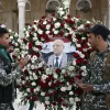 صورة لجنود يقفون أمام إكليل زهور يحمل صورة شخصية مهمة.