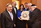 Six personnes souriantes tiennent un panneau en pierre avec un motif symbolique.