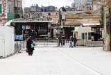 Un checkpoint tenu par l'armée israélienne dans le centre d'Hébron. La rue Chuhada, parsemée de checkpoints, était il y a quelques années une des plus fréquentées de la ville. Aujourd'hui, elle est divisée en deux parties par un muret. Les trois quarts de la chaussée sont réservés aux colons, qui peuvent y circuler avec leur véhicule. Le quart restant, piéton, est le point de passage palestinien. Il ne donne accès qu'au souk, et à la mosquée d'Abraham. Passé le lieu de culte, la rue est strictement interdite aux Palestiniens qui en ont été dépossédés. À la sortie de la ville, cette rue traverse la colonie ultra-orthodoxe de Kyriat Arba, ou vivent près de 8 000 personnes.