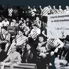 A diverse crowd of people sits in protest, holding signs advocating for freedom of expression.