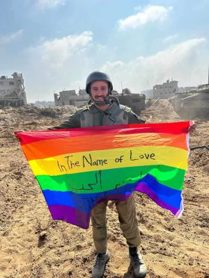 Un soldat tient un drapeau arc-en-ciel dans un paysage dévasté.