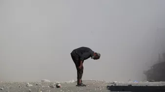 Un homme âgé se penche, entouré de débris et de poussière.