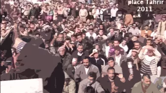 L'image représente une foule massive réunie sur la place Tahrir au Caire en 2011. On peut voir des centaines de personnes assises et levant les mains, probablement dans un acte de protestation ou de soutien. L'environnement semble géré avec une forte présence humaine, et l'ambiance est empreinte d'intensité et d'engagement. Le texte sur l'image indique le lieu et la date de l'événement, suggérant une manifestation historique.