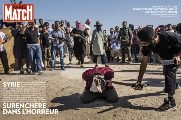 L'image semble représenter une scène dramatique dans un contexte de conflit. Elle montre un groupe de personnes, probablement dans un environnement de guerre, où des individus armés sont présents. Au premier plan, une personne est à genoux, apparemment soumise à des actes de violence, entourée par d'autres qui semblent observer la situation. L'atmosphère est tendue et illustre des thèmes de violence et de conflit, mettant en évidence des tensions entre différentes factions. Les éléments de l'image témoignent d'un contexte difficile et tragique.