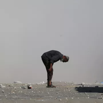 Un homme âgé se penche, entouré de débris et de poussière.
