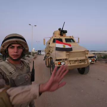 Un soldat égyptien lève la main près d'un véhicule militaire équipé.