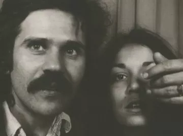 Un homme avec une moustache et une femme montrant un doigt vers l'objectif.