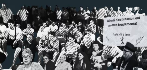 A diverse crowd of people sits in protest, holding signs advocating for freedom of expression.