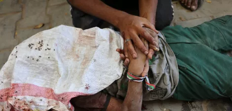 Une personne blessée, allongée au sol, entourée de mains qui l'aident.