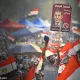 L'image montre une grande foule de manifestants brandissant des drapeaux égyptiens. Au premier plan, un homme lève une pancarte avec le portrait de Mohamed Morsi, qui était le président de l'Égypte. Les participants semblent enthousiasmés et mobilisés, reflétant une atmosphère de rassemblement populaire et d'engagement politique. Le paysage est rempli de tentes et d'une multitude de personnes, créant une impression de solidarité.