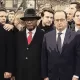 L'image montre un groupe de personnes en émoi, rassemblées dans un cadre public, probablement lors d'un événement solennel. On peut y voir des figures politiques en costumes, dont certaines portent des démarches sérieuses et concentrées. L'ambiance semble être empreinte de gravité et de solidarité. Les participants sont alignés et se regardent, ce qui indique une atmosphère de recueillement ou de soutien mutuel.