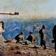 L'image montre un groupe de soldats situés sur un sommet de montagne. À gauche, un char de combat est visible, sa tourelle tournée vers l'avant. Les soldats sont en uniformes militaires, certains semblent assis ou se tiennent debout, avec des paysages montagneux s'étendant en arrière-plan. L'environnement paraît aride, et la lumière donne une atmosphère de calme malgré la présence militaire. Les couleurs de l'image évoquent une certaine nostalgie, suggérant qu'elle pourrait provenir d'une période passée, peut-être de la guerre.