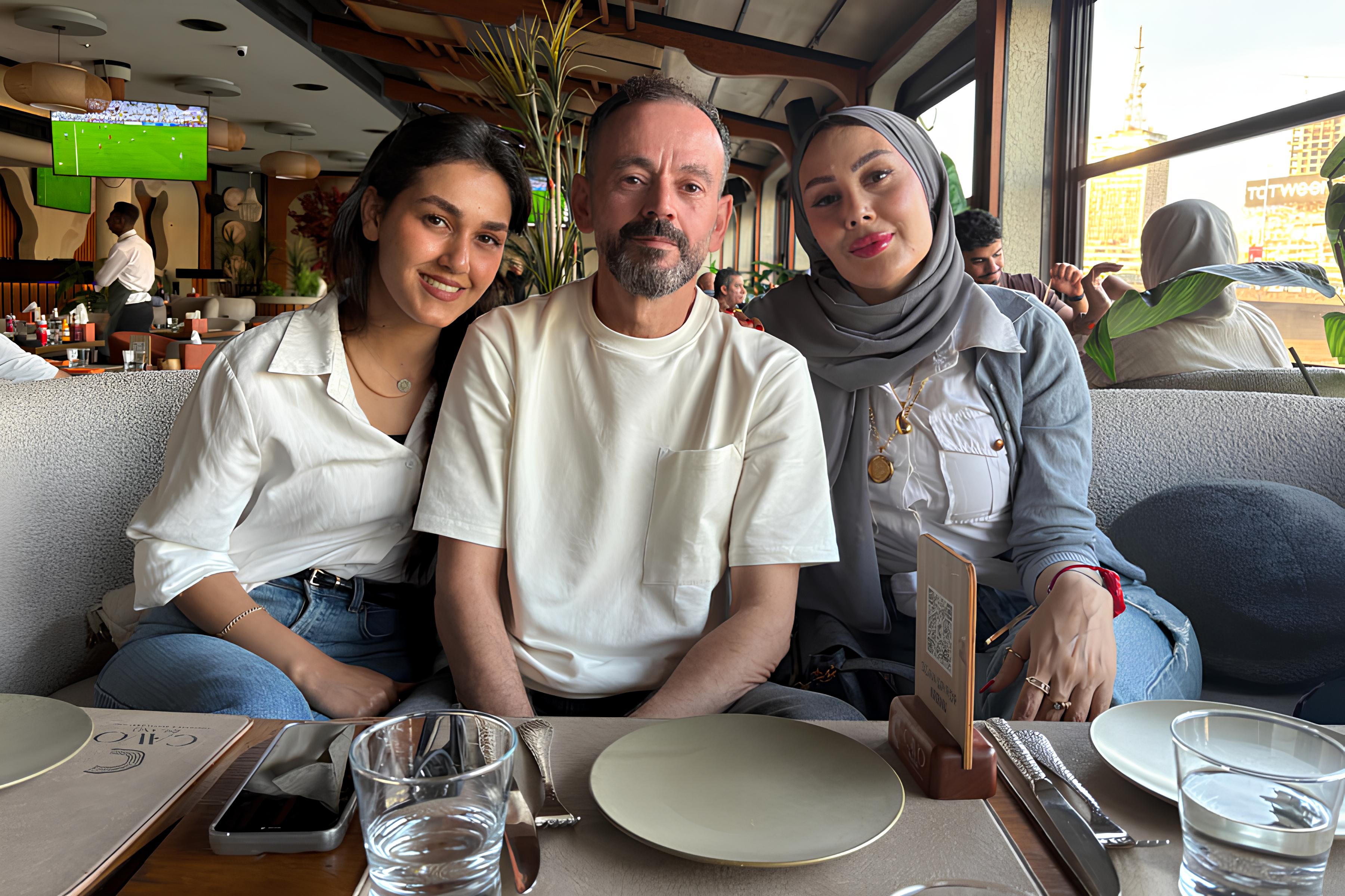 Tre persone sorridono sedute a un tavolo in un ristorante elegante.