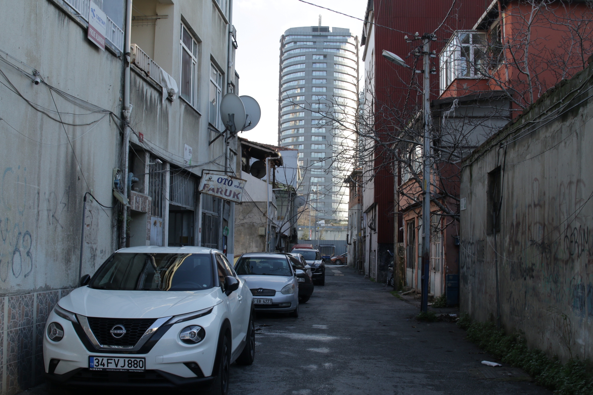 Ruelle étroite avec des maisons anciennes et une tour moderne en arrière-plan.