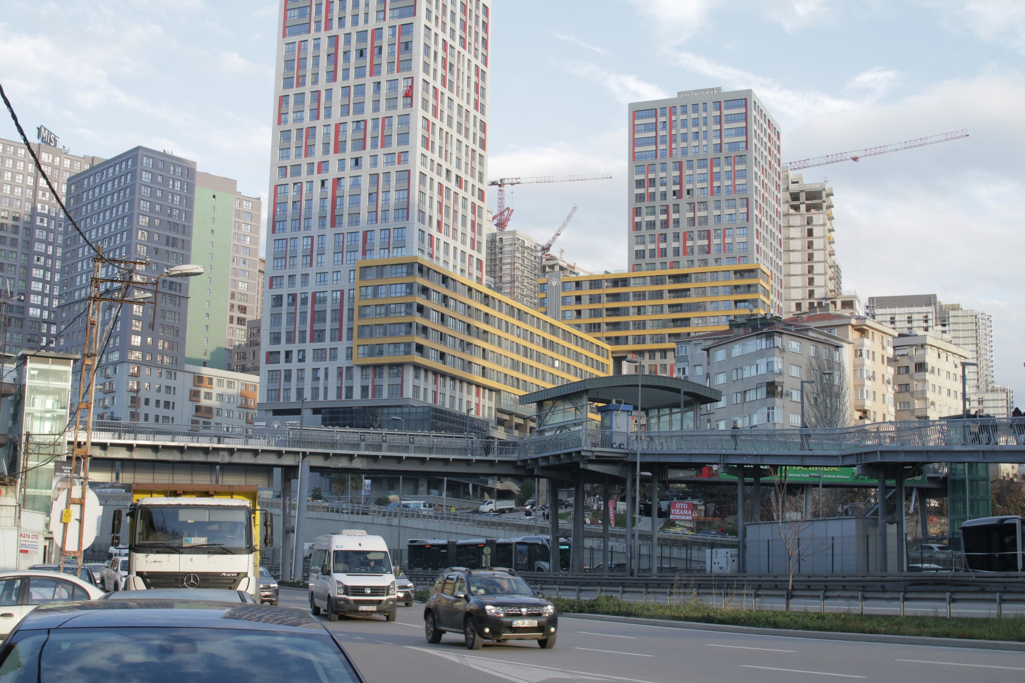 Immeubles modernes et hauts, circulation urbaine animée en bas. Ciel nuageux.