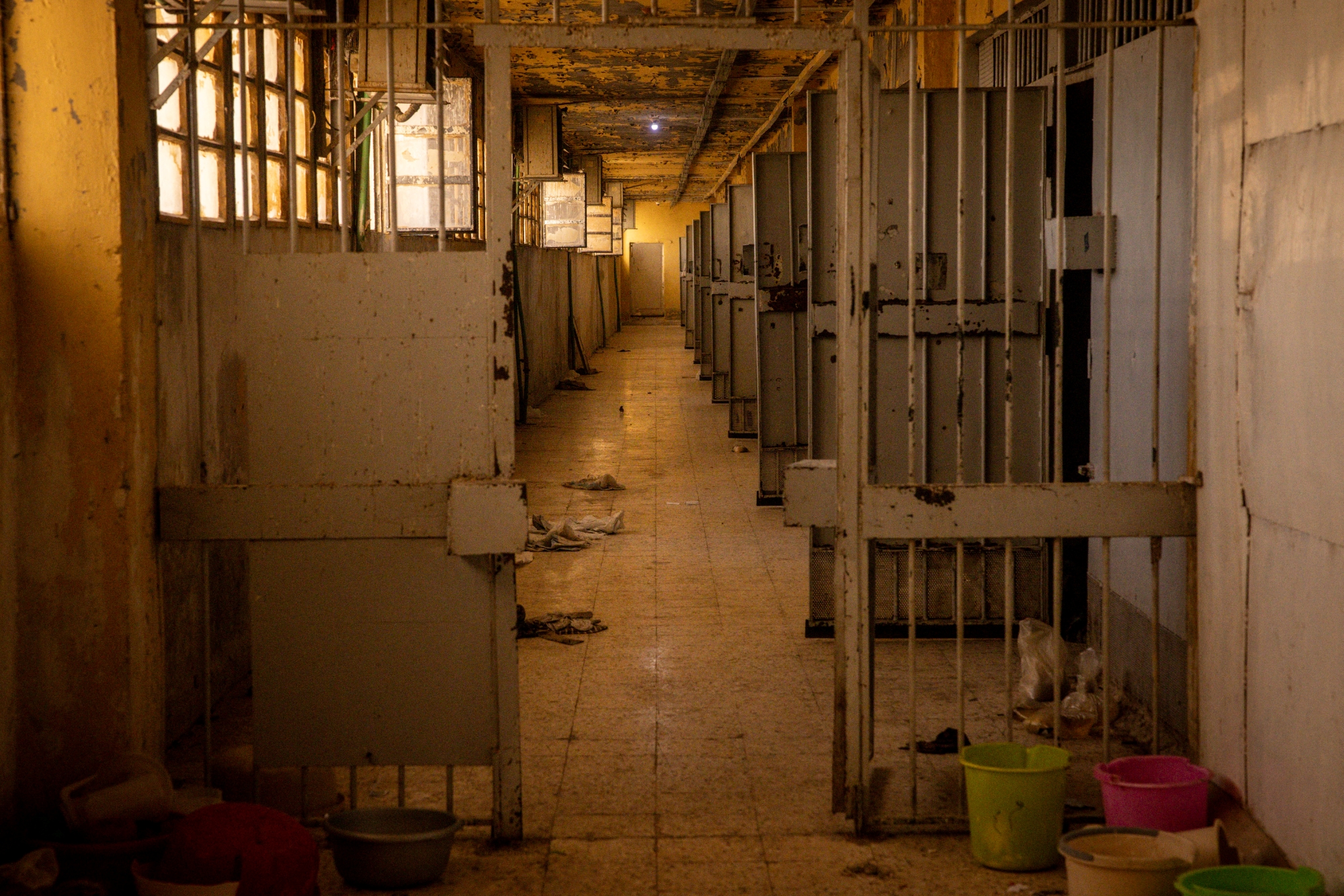 Couloir désert d'une structure, avec des cages vides et des murs en détérioration.