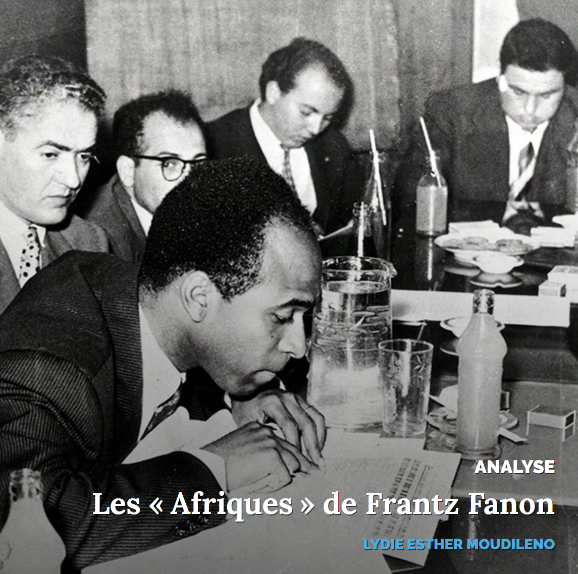 Groupe d'hommes concentrés autour d'une table, discutant lors d'une réunion.