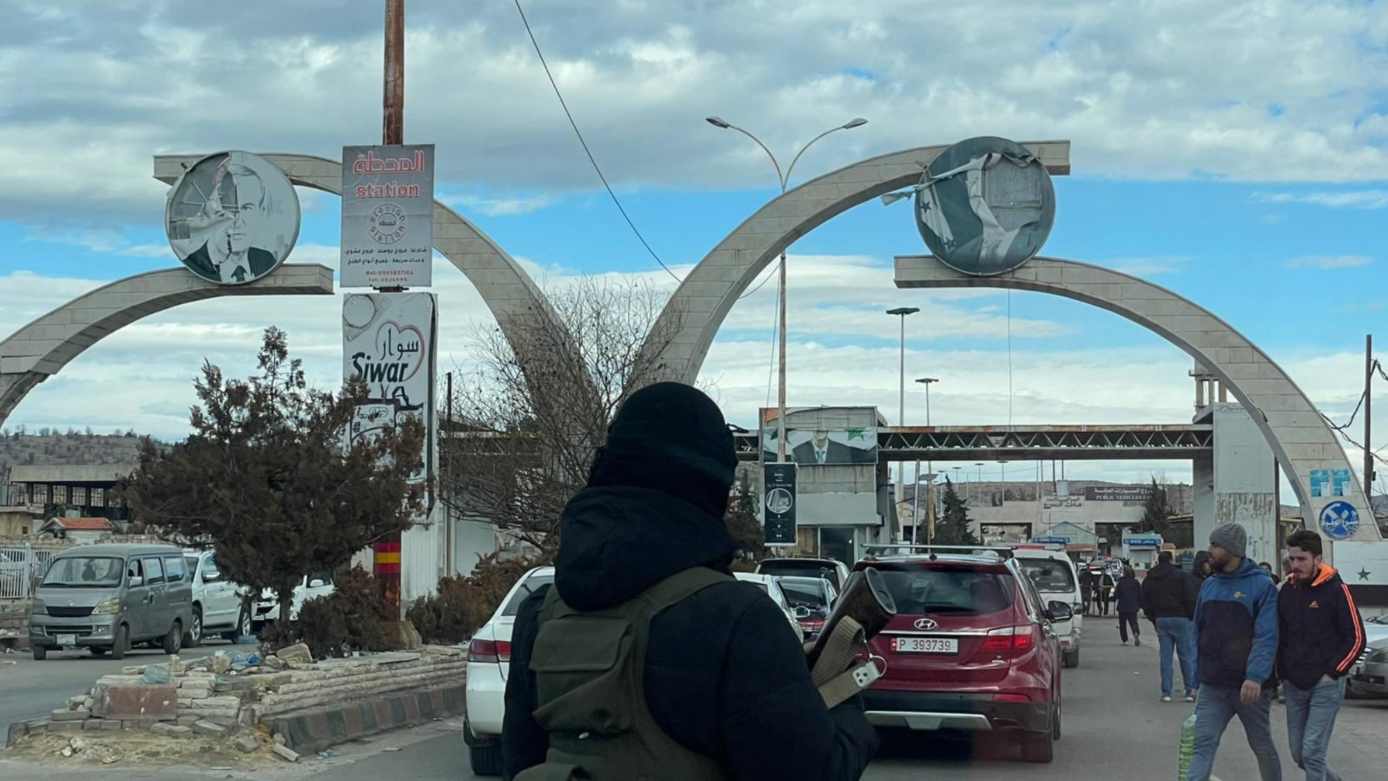 صورة لبوابة كبيرة تتوسطها أعمدة، وأجواء حضرية مزدحمة بالسيارات والمارة.