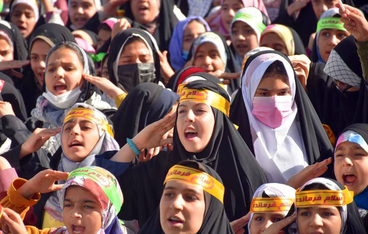 تظهر الصورة مجموعة من الفتيات يرتدين الحجاب، وهن يحتفلن أو يشاركن في فعالية جماعية. الفتيات متمركزات في مجموعة، ويبدين حماسًا ونشاطًا، حيث يرفعن أياديهن ويعبرن عن الفرح أو الحماسة. بعضهن يرتدين عصبات على الرأس مكتوب عليها كلمات تبدو تعبيرية. الجو العام في الصورة يوحي بالاحتفال والطاقة الإيجابية.