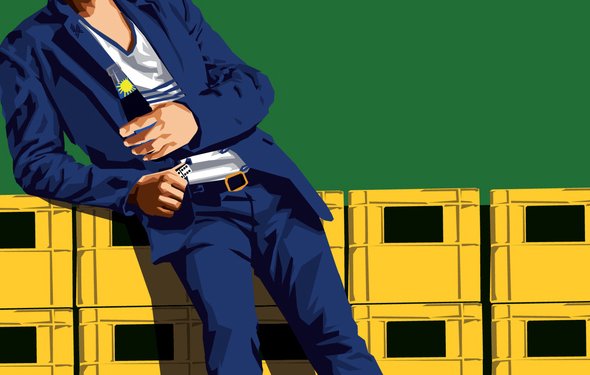 الصورة تظهر شابًا يرتدي ملابس عصرية، حيث يرتدي بدلة زرقاء وقميصًا أبيض. يُعتمر قبعة حمراء ويستخدم نظارات شمسية. يتكئ على صناديق صفراء، ما يعطي انطباعًا غير رسمي وعصري. تعكس الألوان الزاهية والستايل العصري في الصورة أجواء من الحيوية والشباب.