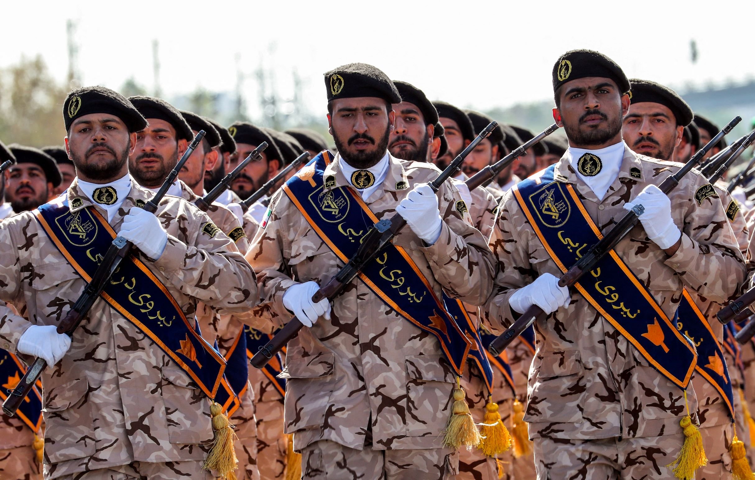 تظهر في الصورة مجموعة من الجنود يرتدون زيًا عسكريًا مموهًا، حيث يحمل كل منهم سلاحًا في يده. وهم يقفون بشكل منظم، ويبدو أنهم يشاركون في حفل استعراض أو مناسبة عسكرية. الجنود يرتدون زينة توحي بأنهم ينتمون إلى قوات معينة، ويظهر في الصورة تعبيرات جادة وملتزمة.