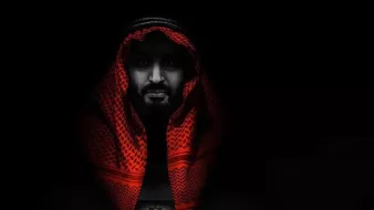 تظهر الصورة شخصية رجل يرتدي الزي التقليدي العربي، حيث يغطي رأسه شماغ أحمر. يمتزج وجهه بالألوان الداكنة، مما يخلق تأثيرًا دراميًا. في الخلفية، يظهر شخص يسير نحو باب مفتوح، مما يرمز إلى الانتقال أو البحث عن الطريق. الأجواء مظلمة وتضفي على الصورة إحساسًا بالغموض والقوة.