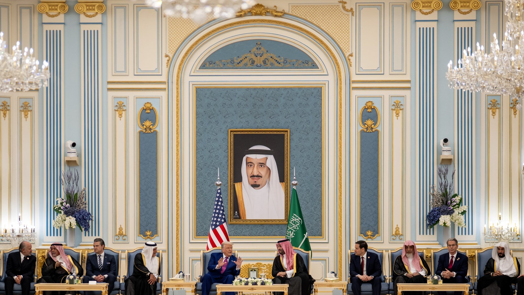 A formal meeting with leaders seated in an ornate room, a large portrait on the wall.