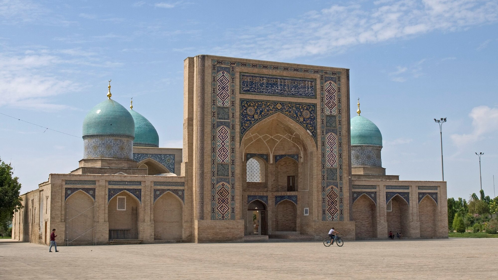A grand structure with blue domes and intricate patterns, set against a clear sky.