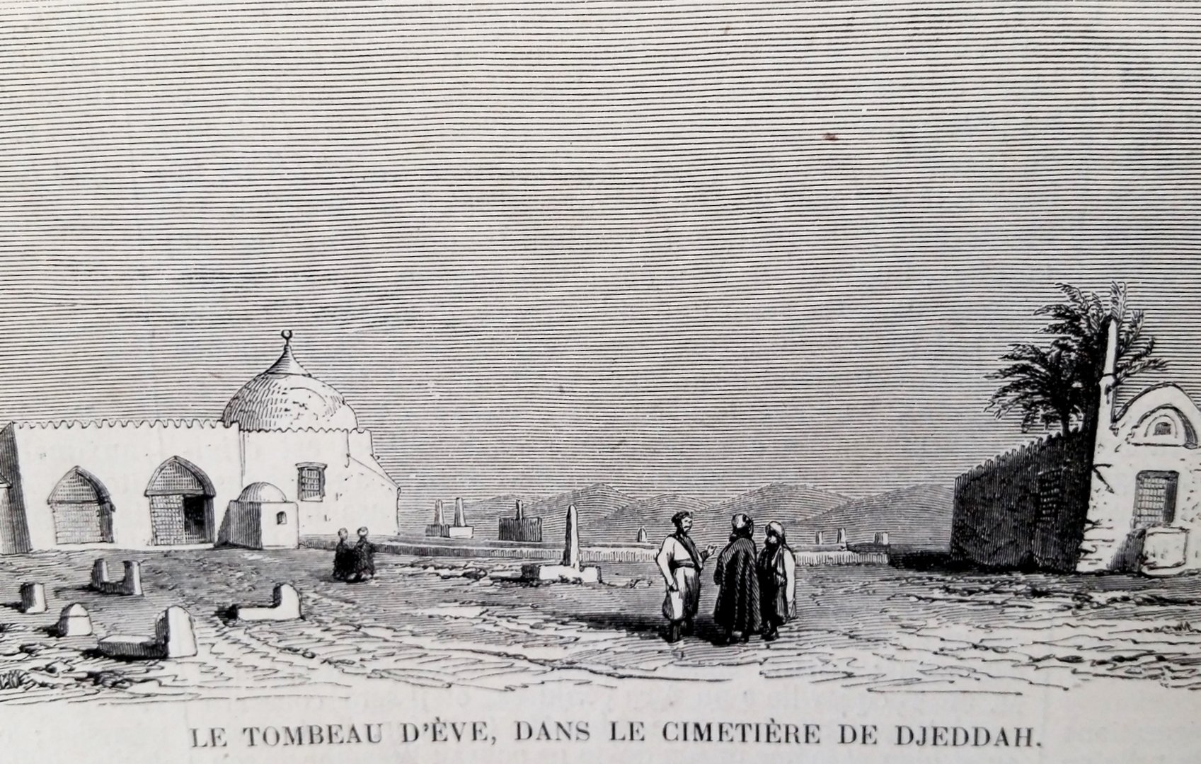 The image depicts a grave site, specifically the Tomb of Eve, in the cemetery of Djeddah (Jeddah). It shows a domed structure that likely marks the tomb, surrounded by a barren landscape. In the foreground, a small group of people is gathered, dressed in traditional attire. The scene is set against a backdrop that suggests a historical or cultural significance, with additional structures or ruins visible in the distance. The overall atmosphere conveys a sense of reverence and history.