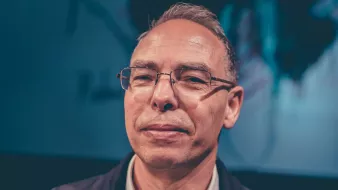 A middle-aged man with glasses and short hair, looking confidently at the camera.