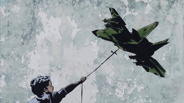 این تصویر گرافیتی را نشان میدهد که یک پسر بچه را در حال دویدن به سمت جلو و گرفتن یک هواپیمای جنگی در انتهای یک رشته نشان میدهد. پسر با شادابی و امید به این هواپیما نگاه میکند، در حالی که دیوار پشت او دستخوش رنگهای کمرنگ و پوسته پوسته است. این اثر نشاندهندهی تضاد بین Innocence (معصومیت) و جنگ است و میتواند تفکرات عمیقتری دربارهی صلح و جنگ را برانگیزد.