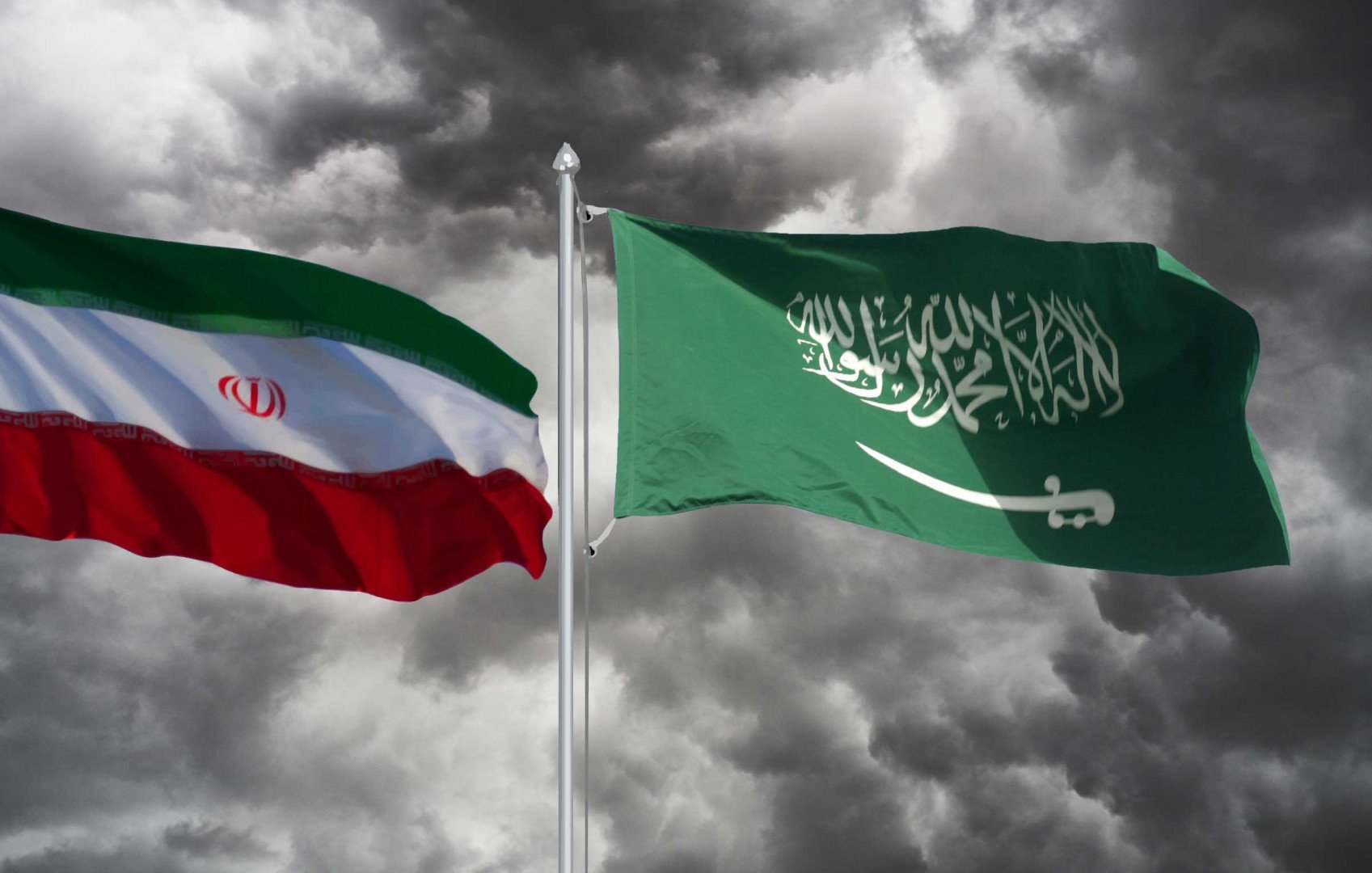 در تصویر، دو پرچم به نمایش درآمدهاند. پرچم چپ، پرچم ایران است که شامل رنگهای سبز، سفید و قرمز به صورت افقی و نشان هشتپر در وسط آن است. پرچم راست، پرچم عربستان سعودی است که رنگ اصلی آن سبز تیره است و در وسط آن نوشته عربی به رنگ سفید وجود دارد. زمینه تصویر ابری و طوفانی به نظر میرسد که حسی از تنش و درگیری را منتقل میکند.