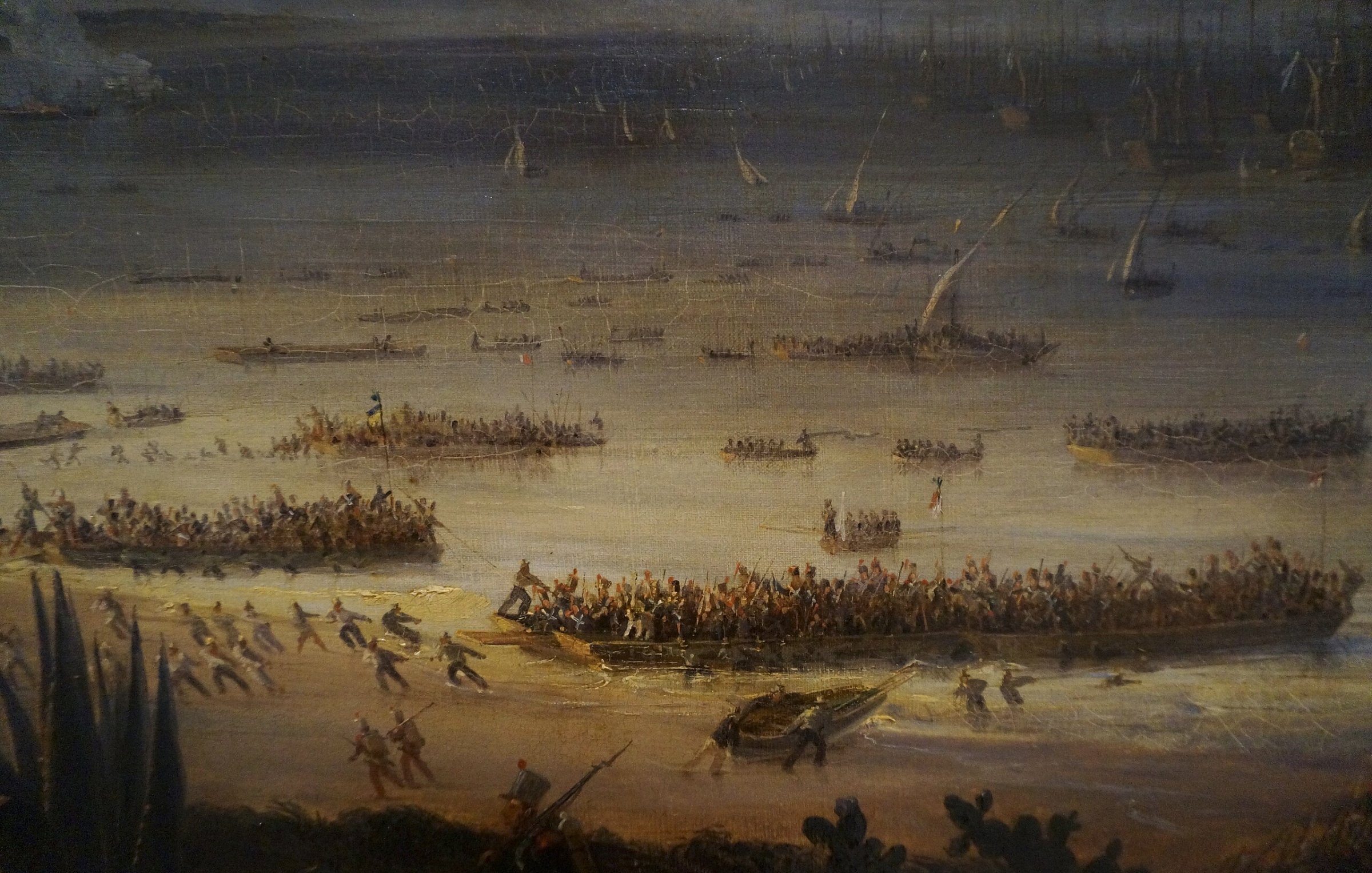 این تصویر یک صحنه دریا را نشان میدهد که در آن گروهی از افراد در حال مبارزه یا جابجایی در کنار ساحل هستند. قایقهای زیادی در آب دیده میشوند و آدمها در حال فعالیتهای مختلفی هستند. فضای کلی پر از حرکت و تنش است.