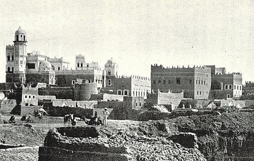 این تصویر نشاندهندهی یک منطقه تاریخی است که در آن ساختمانهای قدیمی با معماری سنتی دیده میشوند. در پسزمینه، چندین ساختمان با سقفهای گنبدی و تزئینات خاص وجود دارد. همچنین افرادی در حال کار در زمینهای جلویی دیده میشوند که ممکن است مشغول کشاورزی یا ساختوساز باشند. این صحنه، حال و هوای زندگی روزمره و تاریخی را در یک جامعه قدیمی به تصویر میکشد.