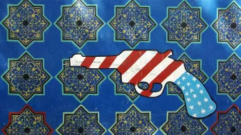 این تصویر شامل یک زمینه آبی با الگوهای هندسی و طراحیهای سنتی است که به رنگهای طلایی و سبز نمایان شدهاند. در وسط تصویر، یک نقاشی از یک تفنگ نمایش داده شده که با رنگهای پرچم ایالات متحده، یعنی سرخ، سفید و آبی، تزئین شده است. طراحی تفنگ با الگوهای زمینه تضاد دارد و به نوعی تأملی از الهام غربی در هنر ایرانی را به تصویر میکشد.