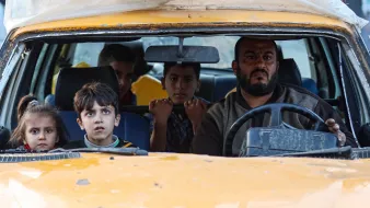 درون یک تاکسی زرد، مردی در حال رانندگی است و چهار کودک با نگاههای حیرتزده نشستهاند.