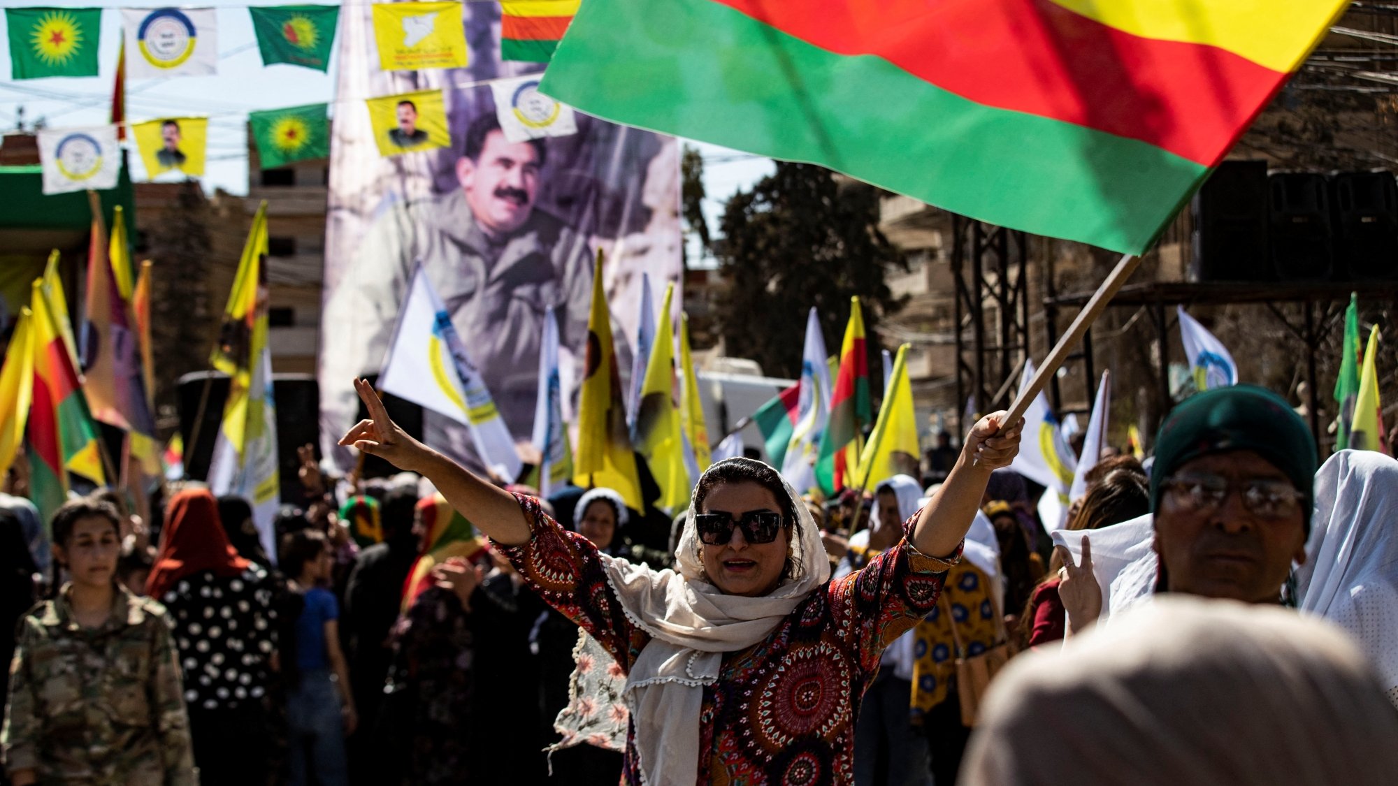 Foule festive brandissant des drapeaux colorés, ambiance de célébration et de solidarité.