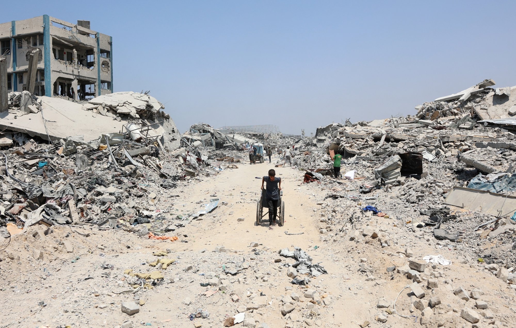 Un chemin au milieu des ruines, une personne en fauteuil roulant avance lentement.