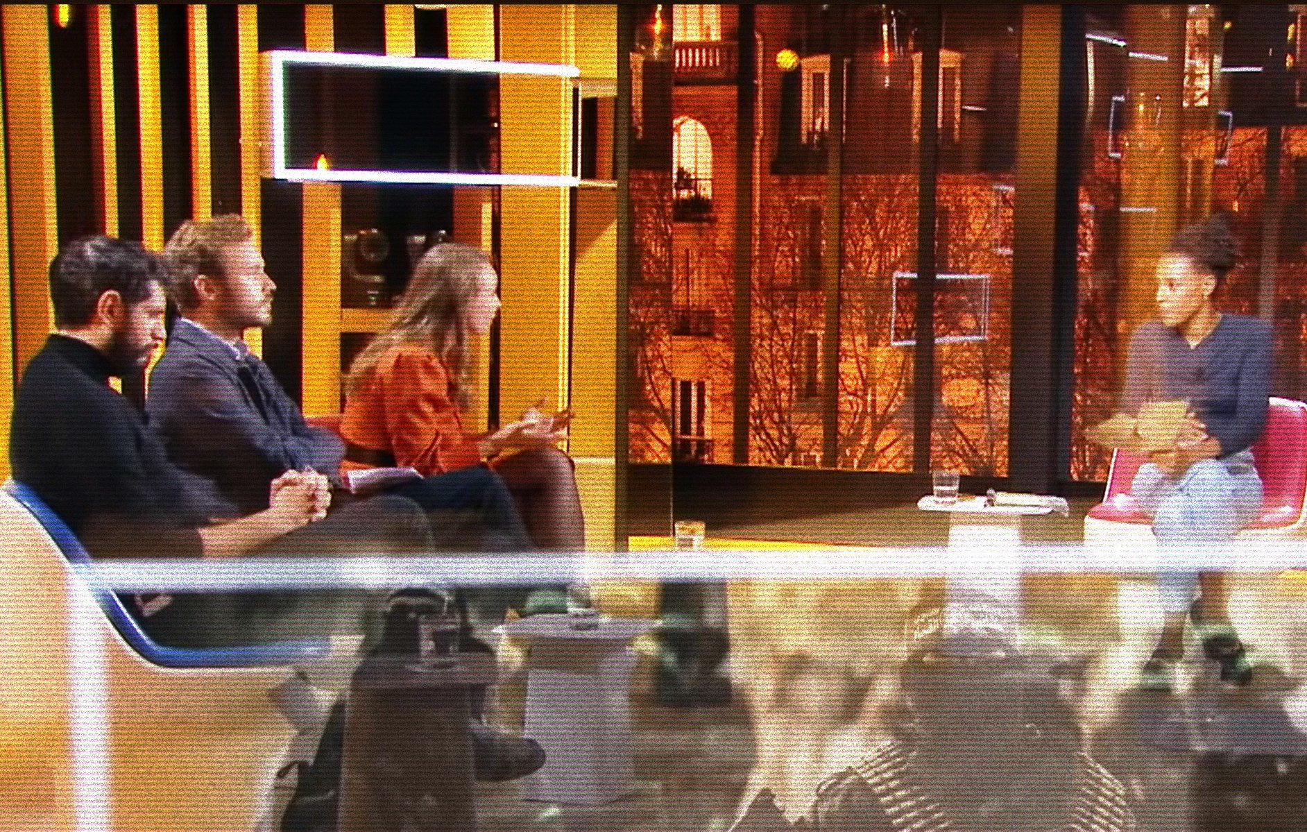 Quatre personnes discutent sur un plateau, avec une vue citadine illuminée en arrière-plan.