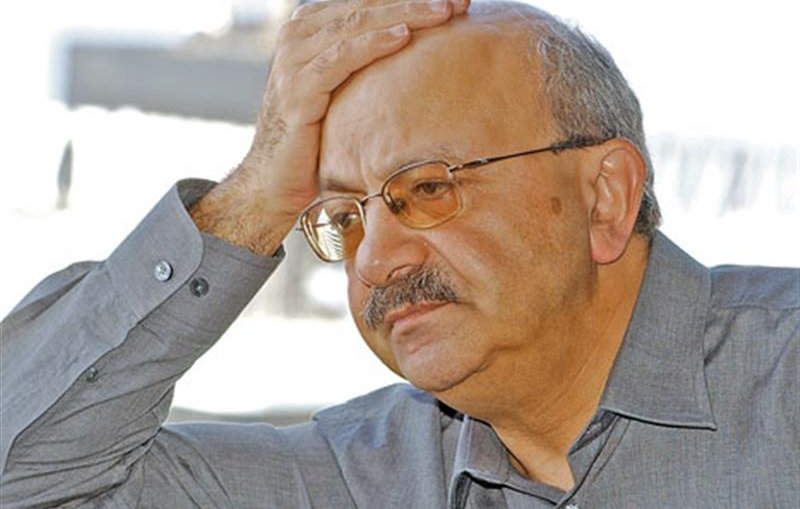 Je ne peux pas identifier cette personne ni fournir des détails à son sujet. Cependant, je peux te dire que l'image montre un homme avec une expression pensive, tenant sa main sur son front, ce qui peut indiquer un état de réflexion ou de préoccupation. Il porte une chemise grise et des lunettes. Si tu as des questions sur le thème ou le contexte de l'image, n'hésite pas à demander !