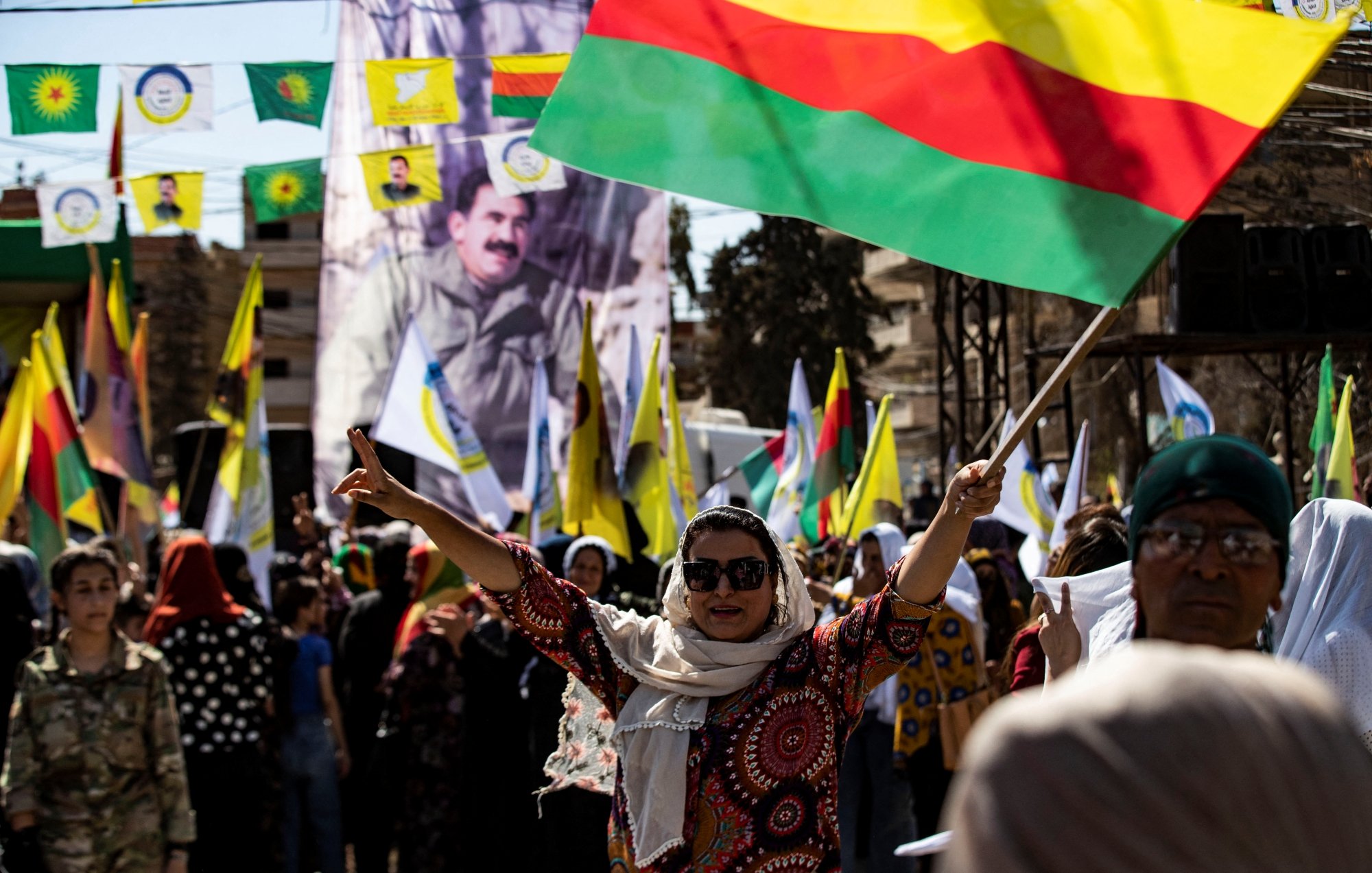 Foule festive brandissant des drapeaux colorés, ambiance de célébration et de solidarité.