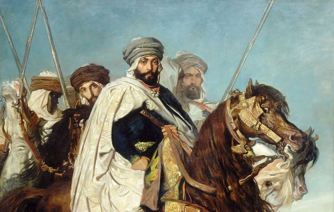 L'image représente un groupe de cavaliers, probablement d'origine orientale, habillés en costumes traditionnels. Au premier plan, un homme est monté sur un cheval majestueux, vêtu d'une tunique ornée et d'un turban. Il semble être le leader ou la figure centrale de ce groupe. Les autres cavaliers en arrière-plan portent également des tenues similaires et tiennent des lances, créant une impression de puissance et de bravoure. Le ciel en arrière-plan est clair, ajoutant une dimension dramatique à la scène. L'ensemble dégage une atmosphère historique et militaire.