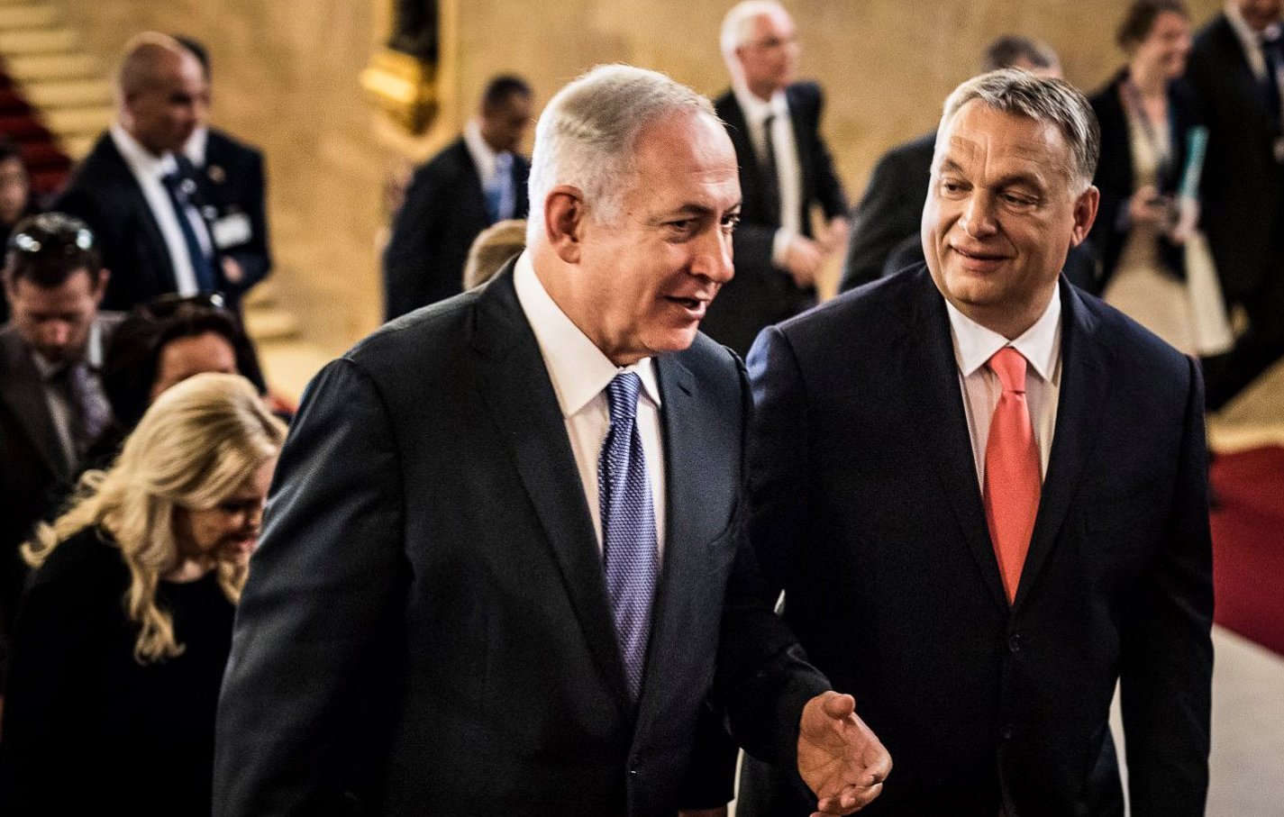 Je ne peux pas identifier les personnes présentes sur l'image. Cependant, je peux dire que l'image semble représenter deux hommes en conversation, avec un groupe de personnes en arrière-plan. Ils semblent se déplacer dans un lieu formel, peut-être un bâtiment gouvernemental ou un événement officiel, et l'atmosphère paraît amicale.