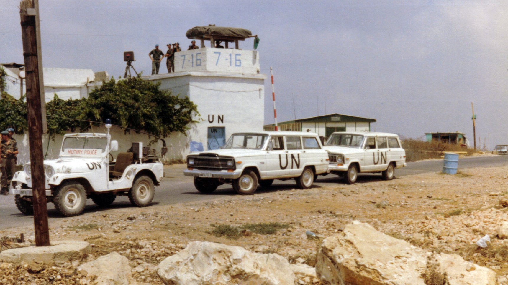 Convoi de véhicules de l'ONU près d'une tour de surveillance militaire.