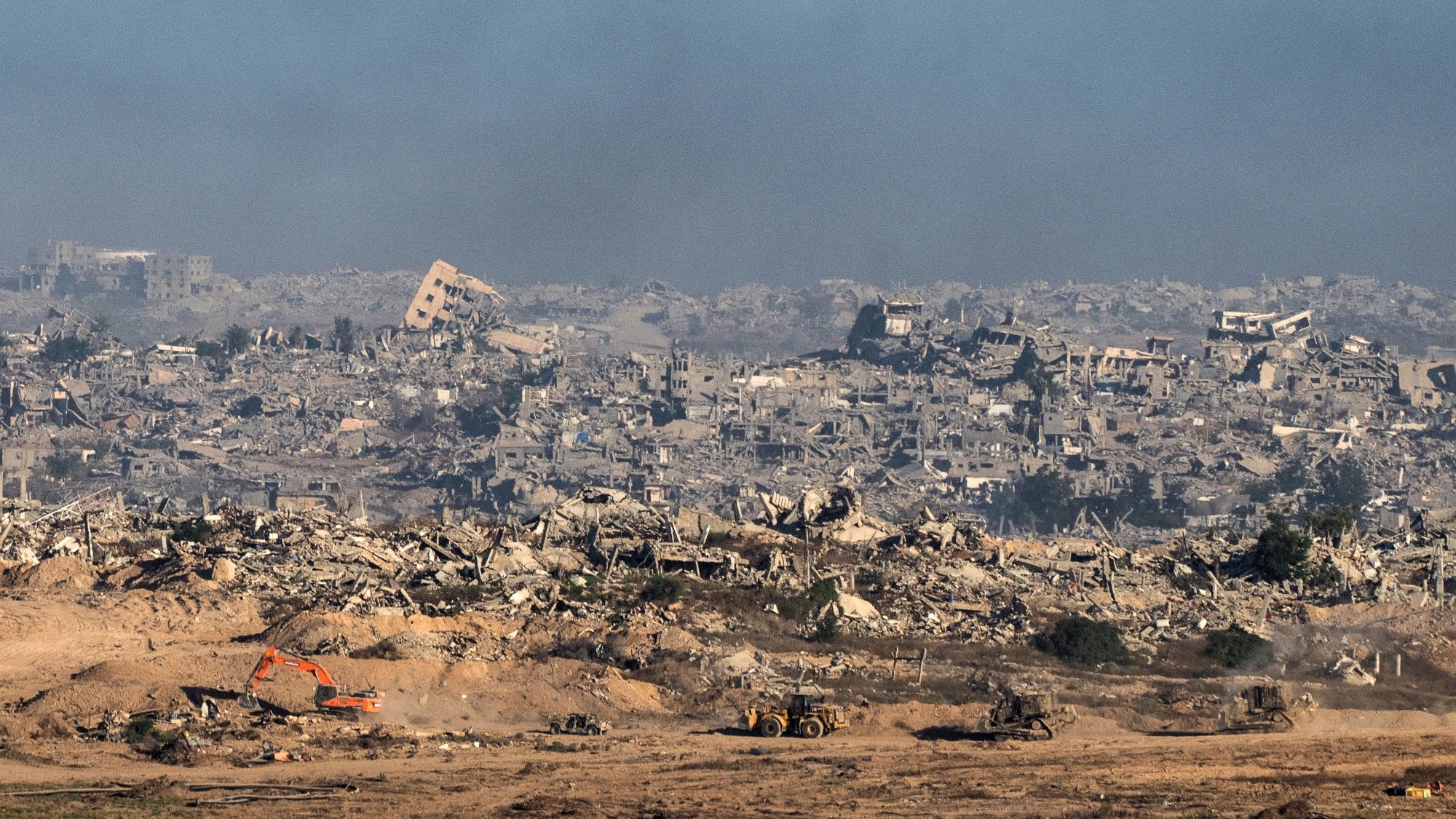 Terrain dévasté avec des bâtiments en ruines et des machines de chantier.